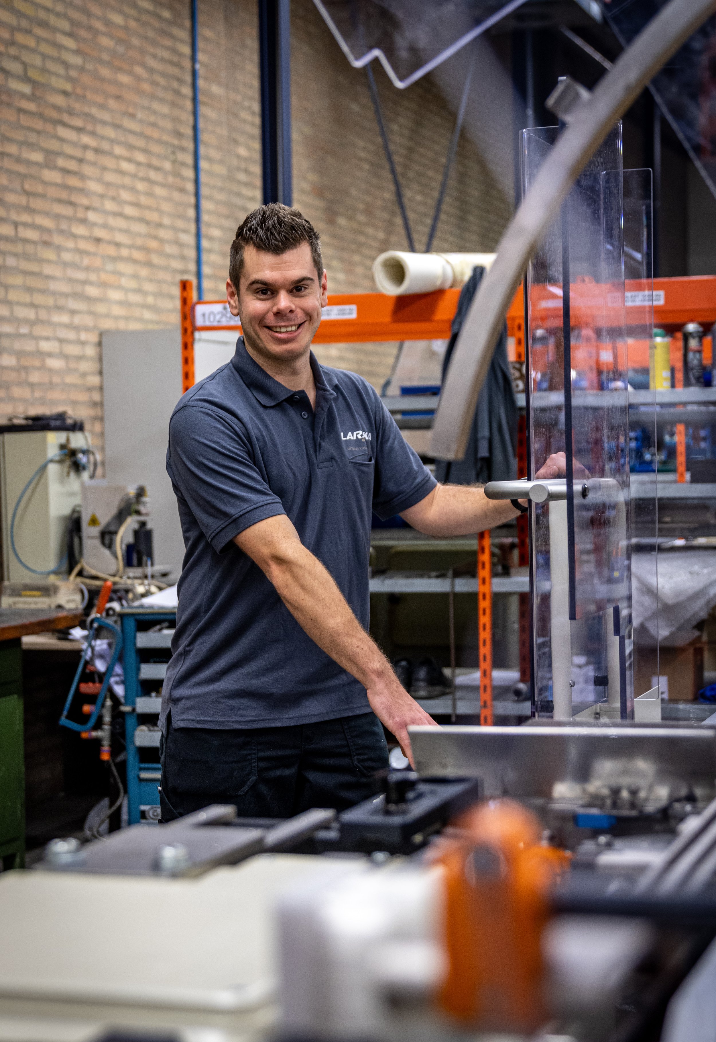 A man from the Lareka team smiling while working at a workbench with tools in an warehouse setting.