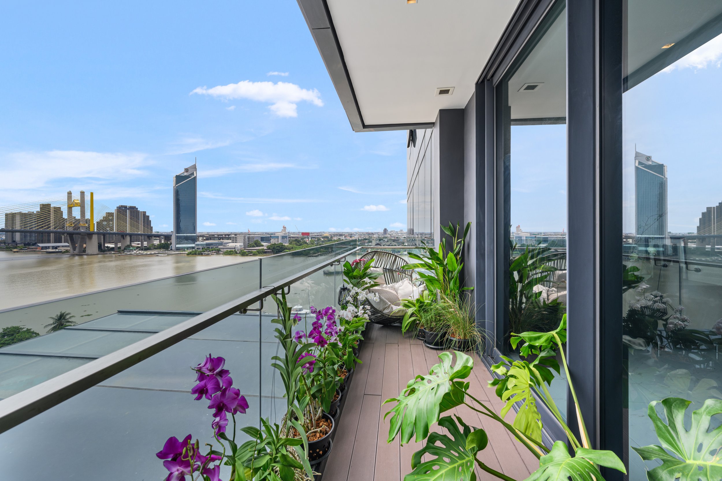 Balcony with orchids, monsteras and palms, overlooking the Chao Phraya River