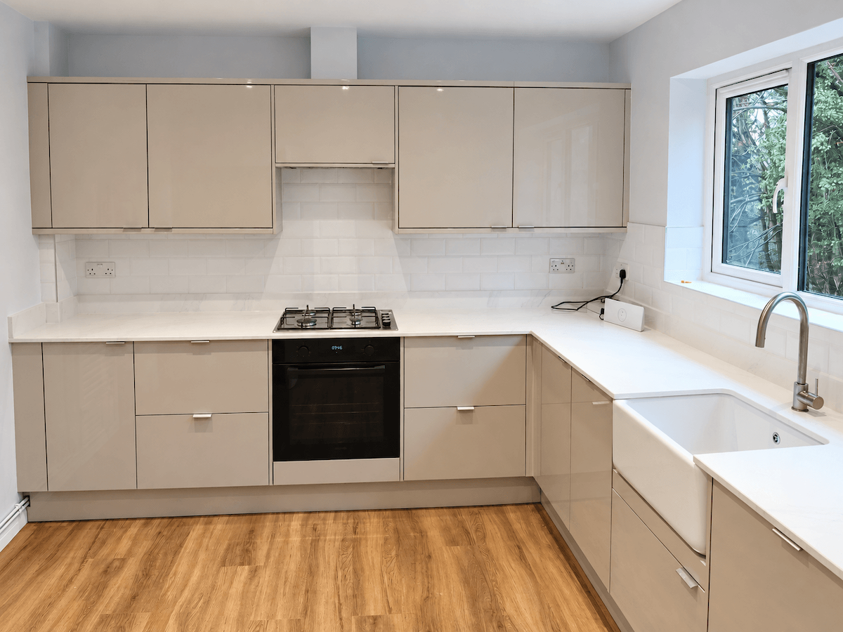 Kitchen with cream cabinets, white worktops, a tiled splashback and wood-effect flooring.