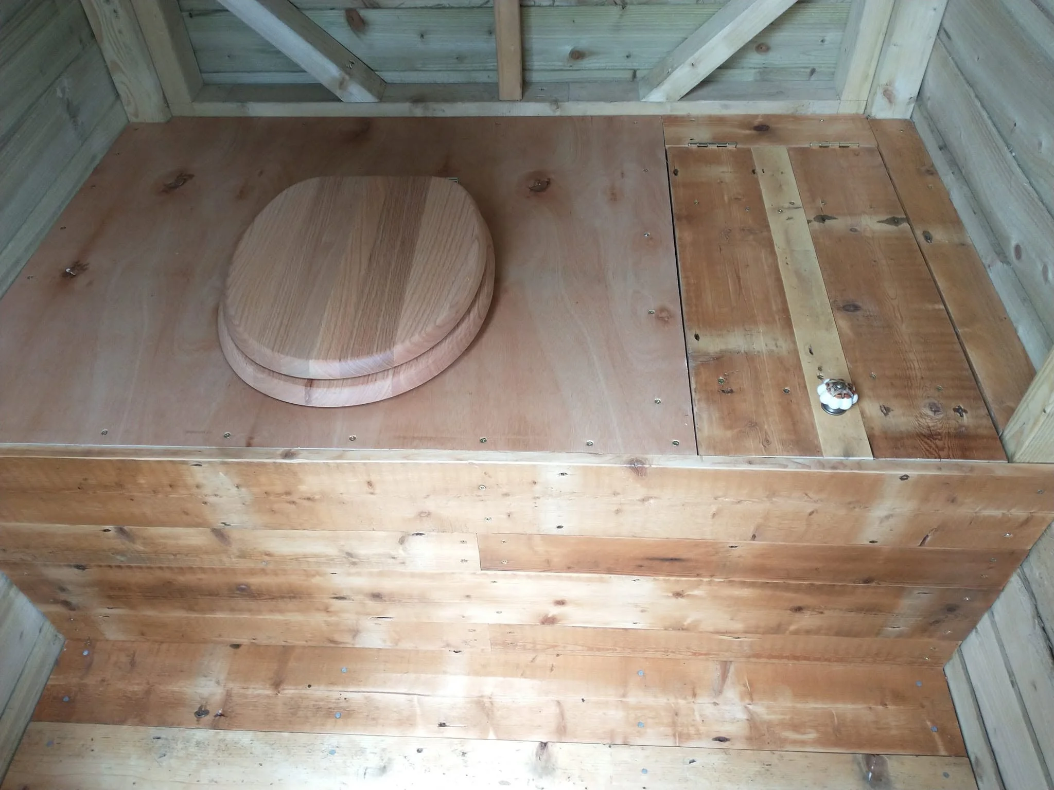 Wooden toilet seat fitted into a timber platform inside the composting toilet.