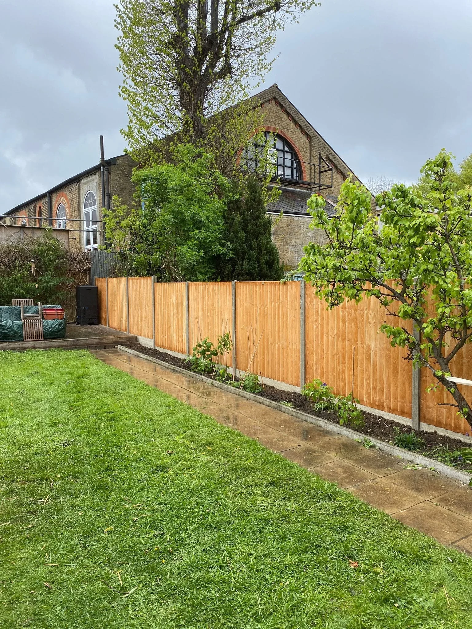 New timber fence panels between concrete posts alongside the garden lawn and planted border.