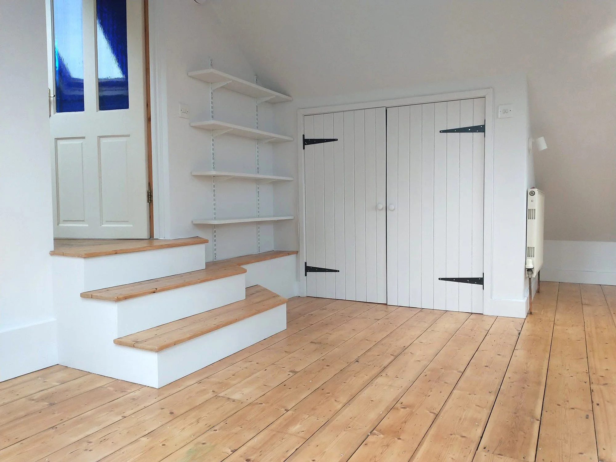Mezzanine with freshly painted white stair risers, shelving and cupboard doors, alongside natural timber treads and floorboards.