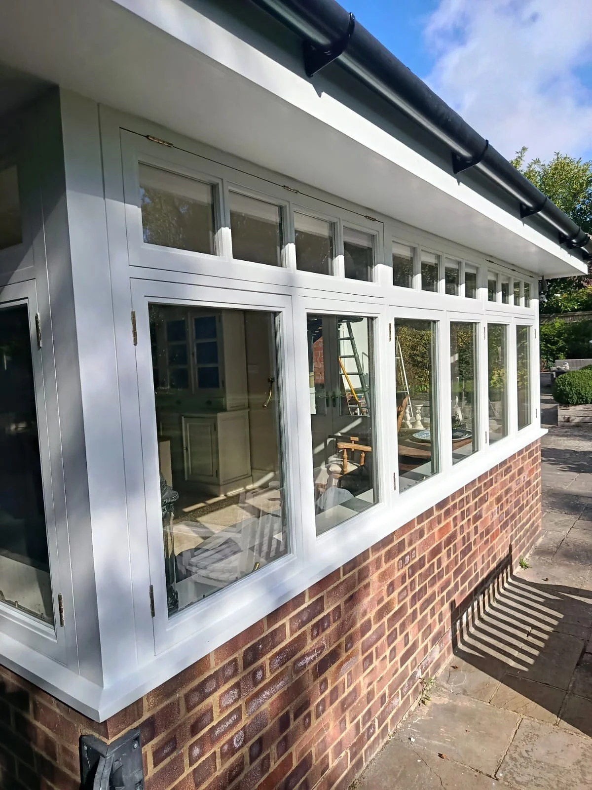 Freshly painted white exterior window frames and surrounding woodwork above a red brick wall.