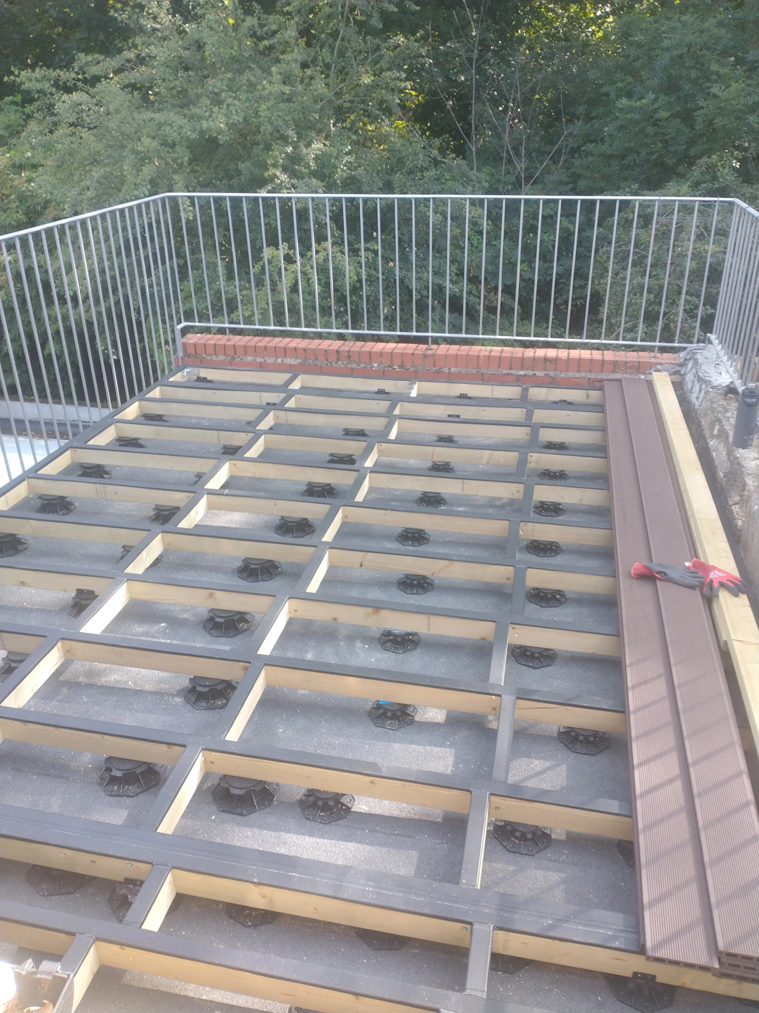 Exposed deck framework on raised supports, with the first composite boards fitted along one edge.
