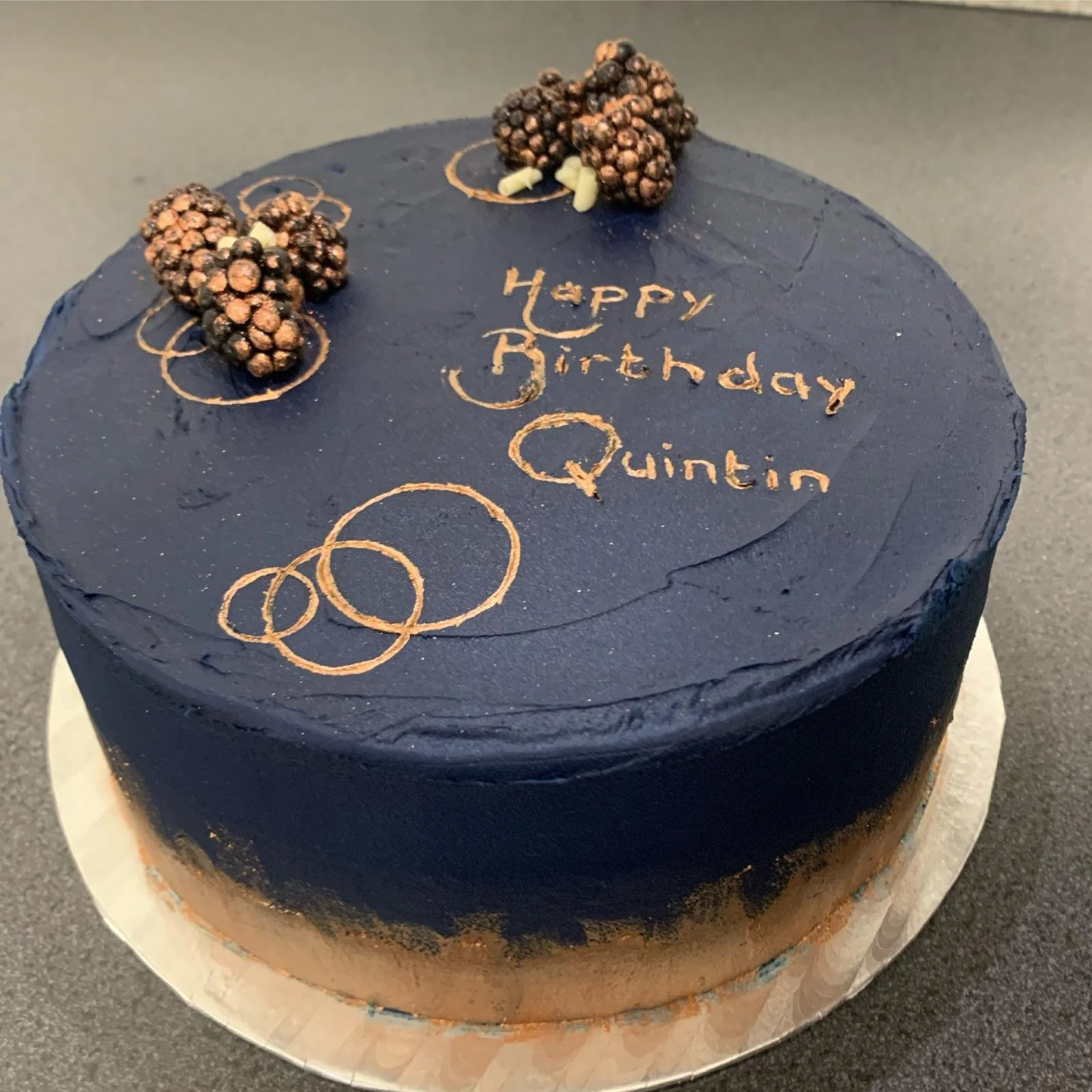 Navy blue birthday cake with gold script lettering, gold rings and chocolate truffles