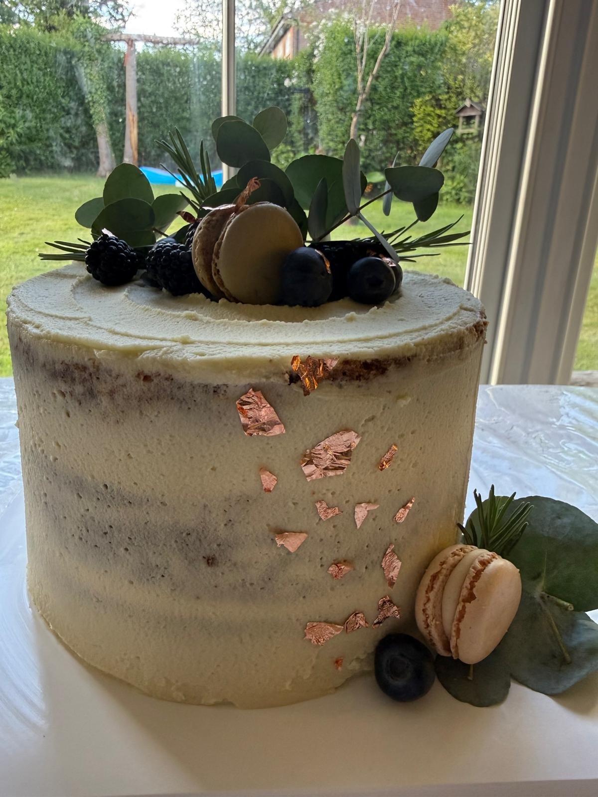 Semi-naked cake with blueberries, macarons and gold leaf