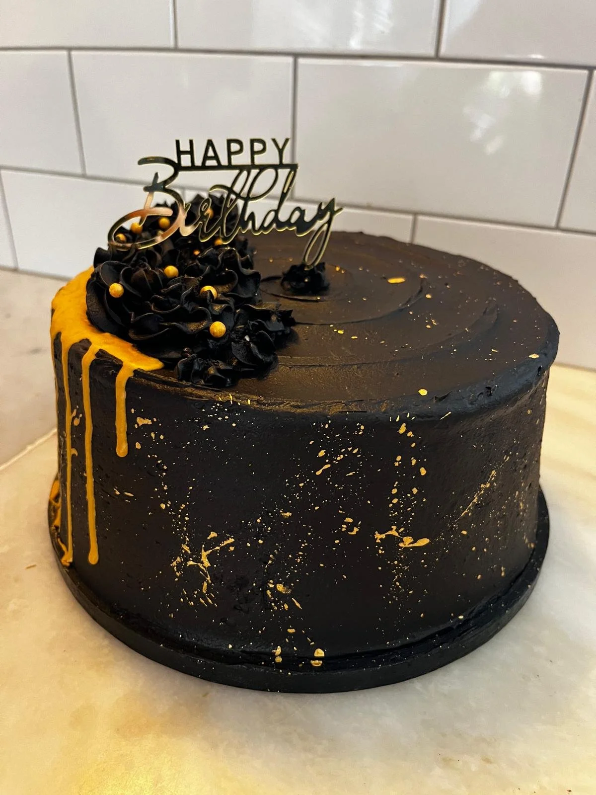 Black birthday cake with gold drip and dark chocolate flowers