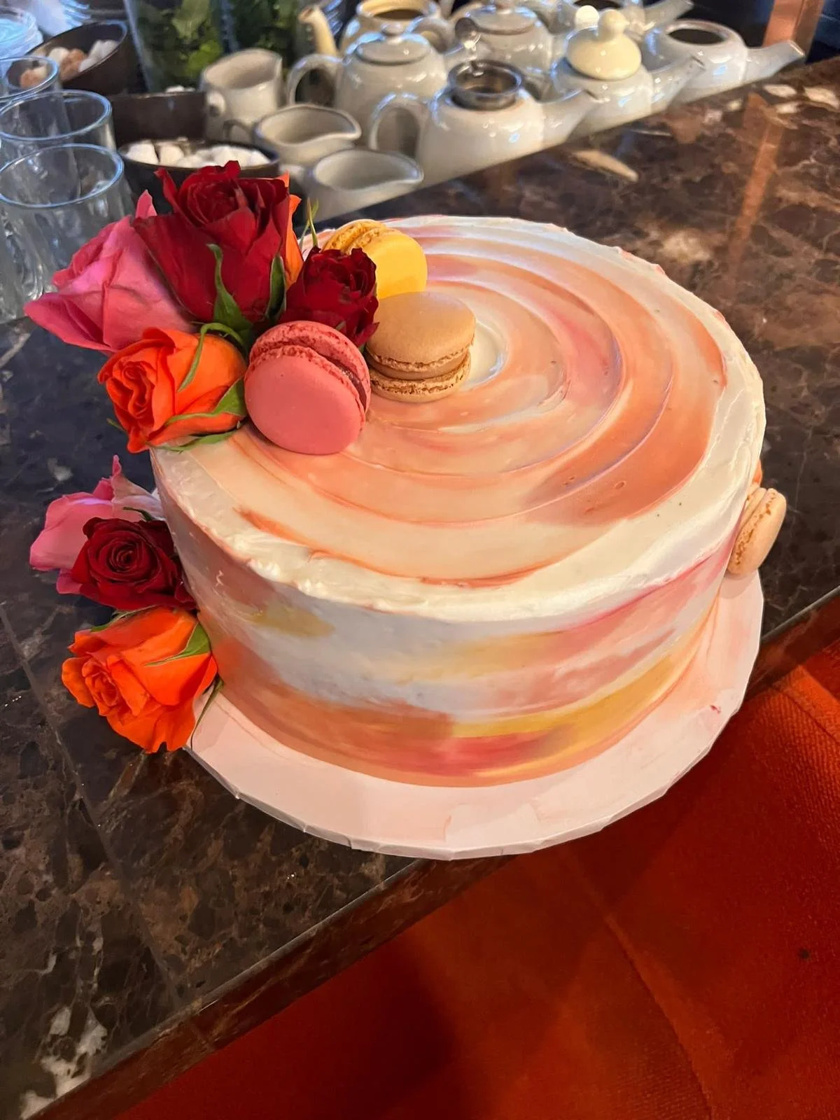 Marbled pink and peach cake with fresh roses and macarons