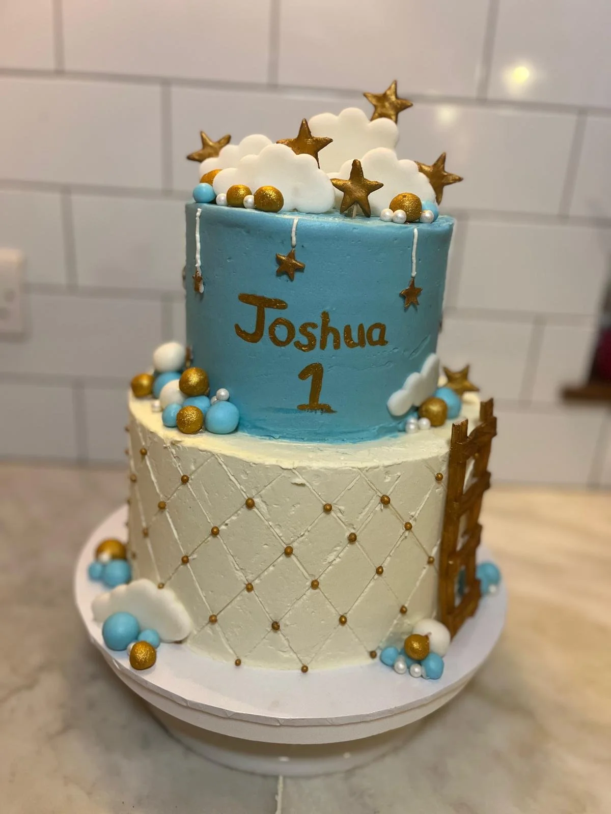 Blue and white first birthday cake with gold stars and clouds