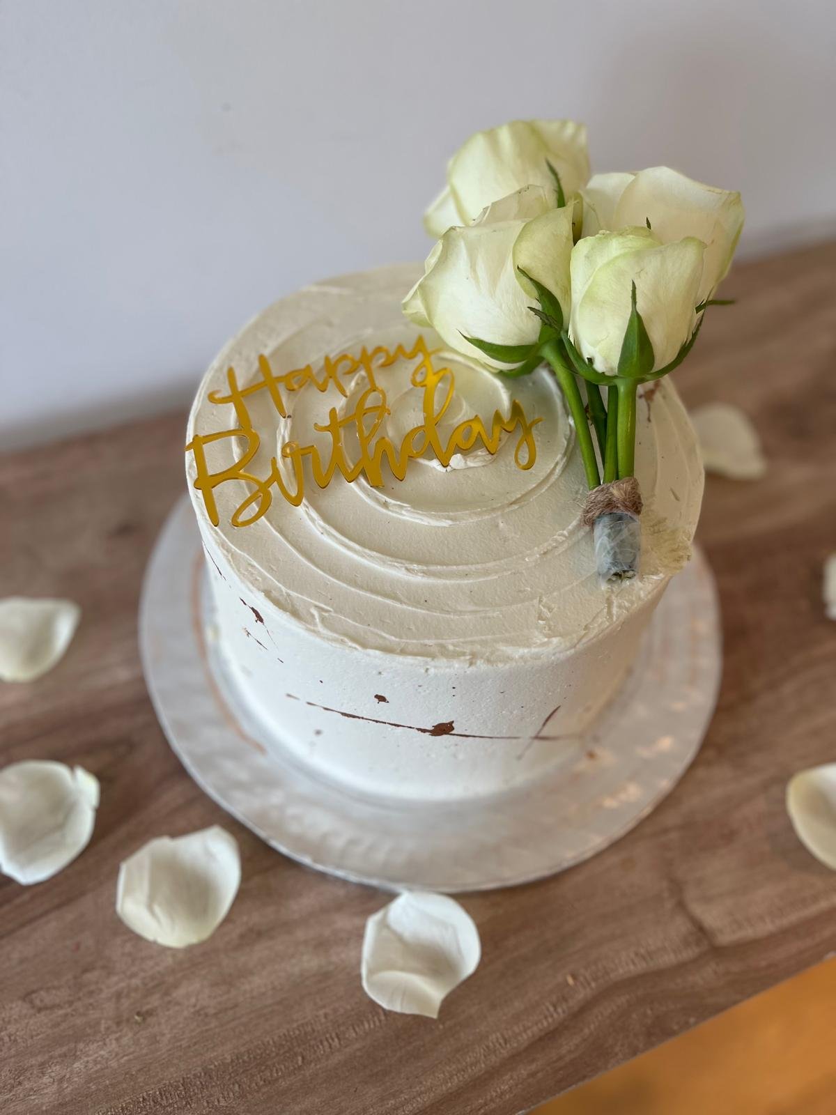 Birthday cake with white roses and gold leaf and a Happy Birthday topper
