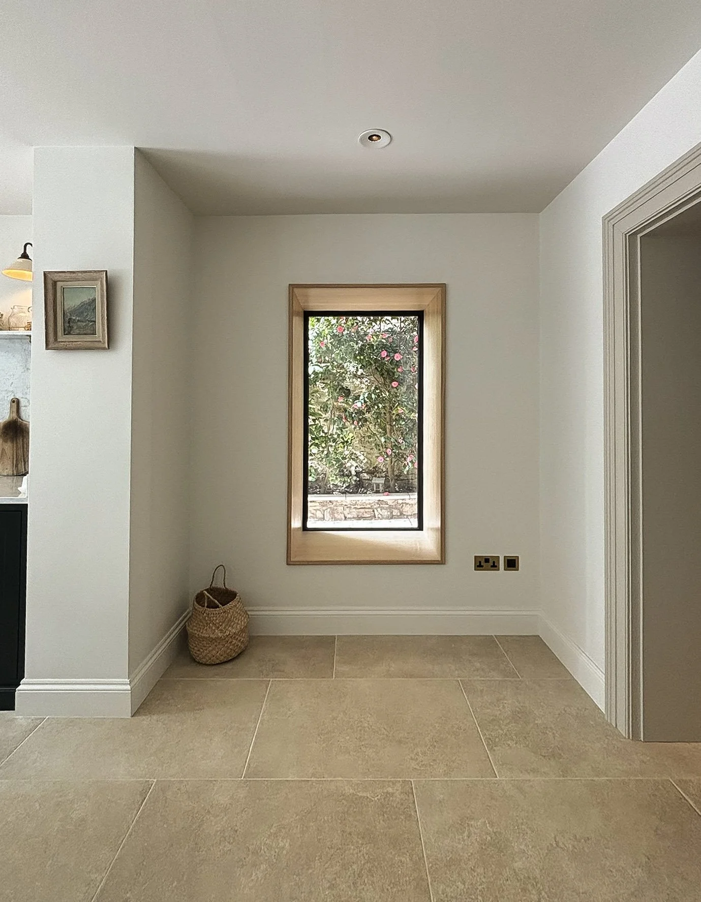 Window set in a deep oak-lined reveal, looking out onto the garden, in a limestone-floored basement in Clifton by JG Build.