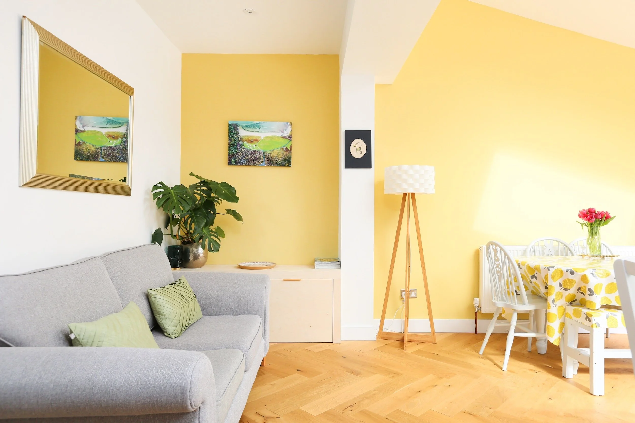 Living area in an open-plan extension with a built-in storage unit in the alcove, yellow painted walls and herringbone parquet flooring, in Bristol by JG Build.