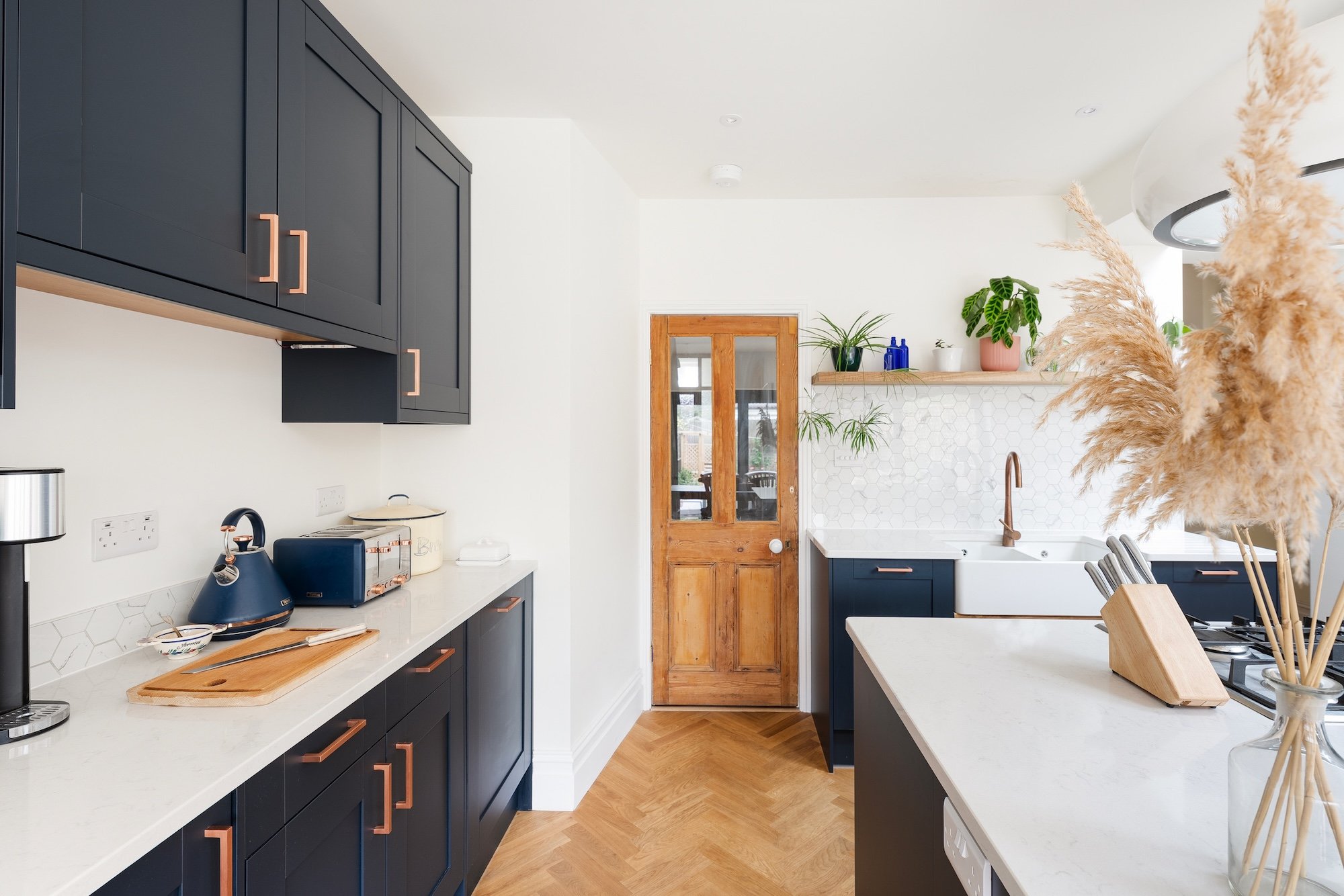 Navy shaker kitchen with copper handles, quartz worktops and oak herringbone flooring in a Bishopston kitchen extension by JG Build.