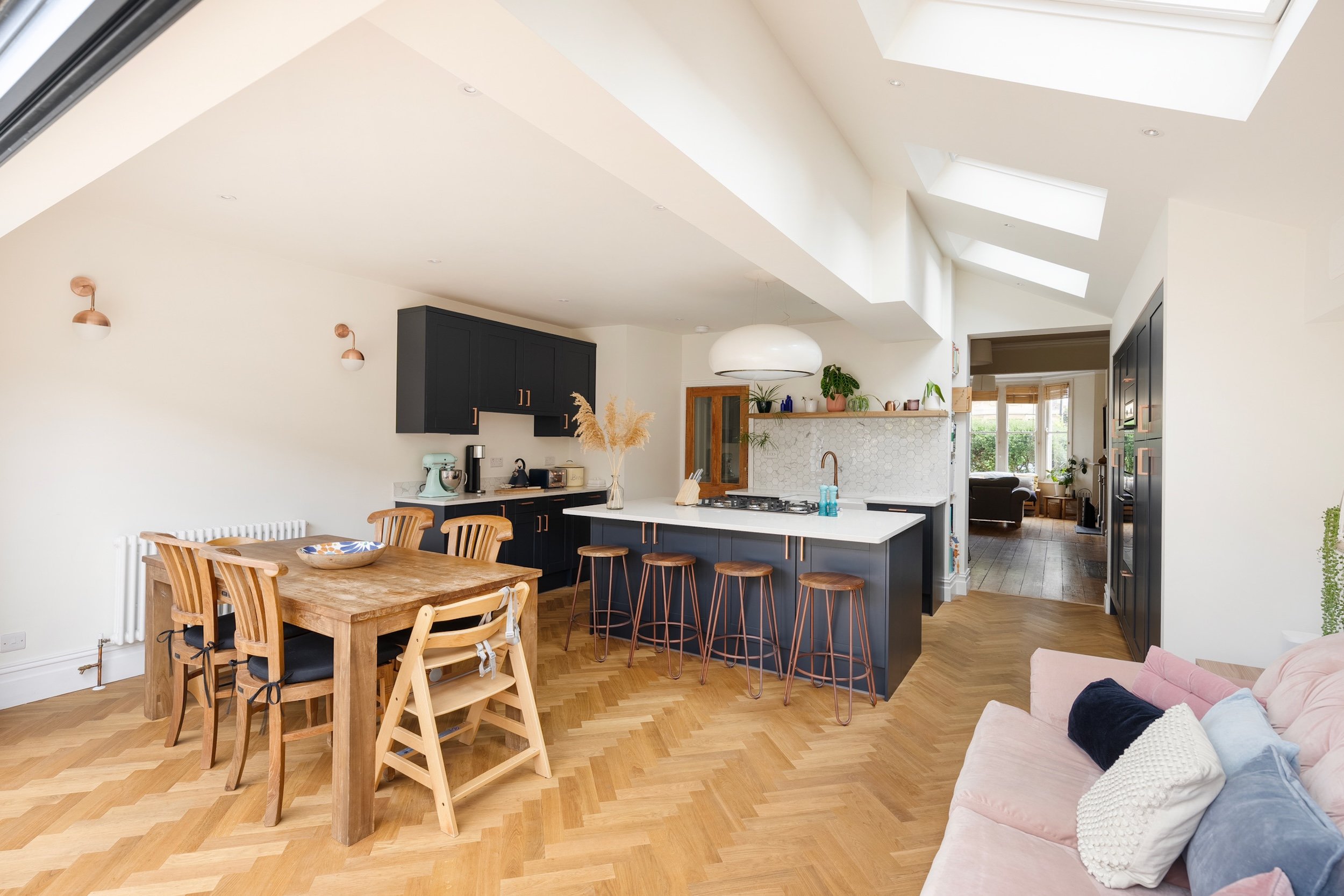 Kitchen extension with a vaulted ceiling, roof lights and oak parquet flooring, with a dining area and a view through to the original front room, in Bishopston by JG Build.