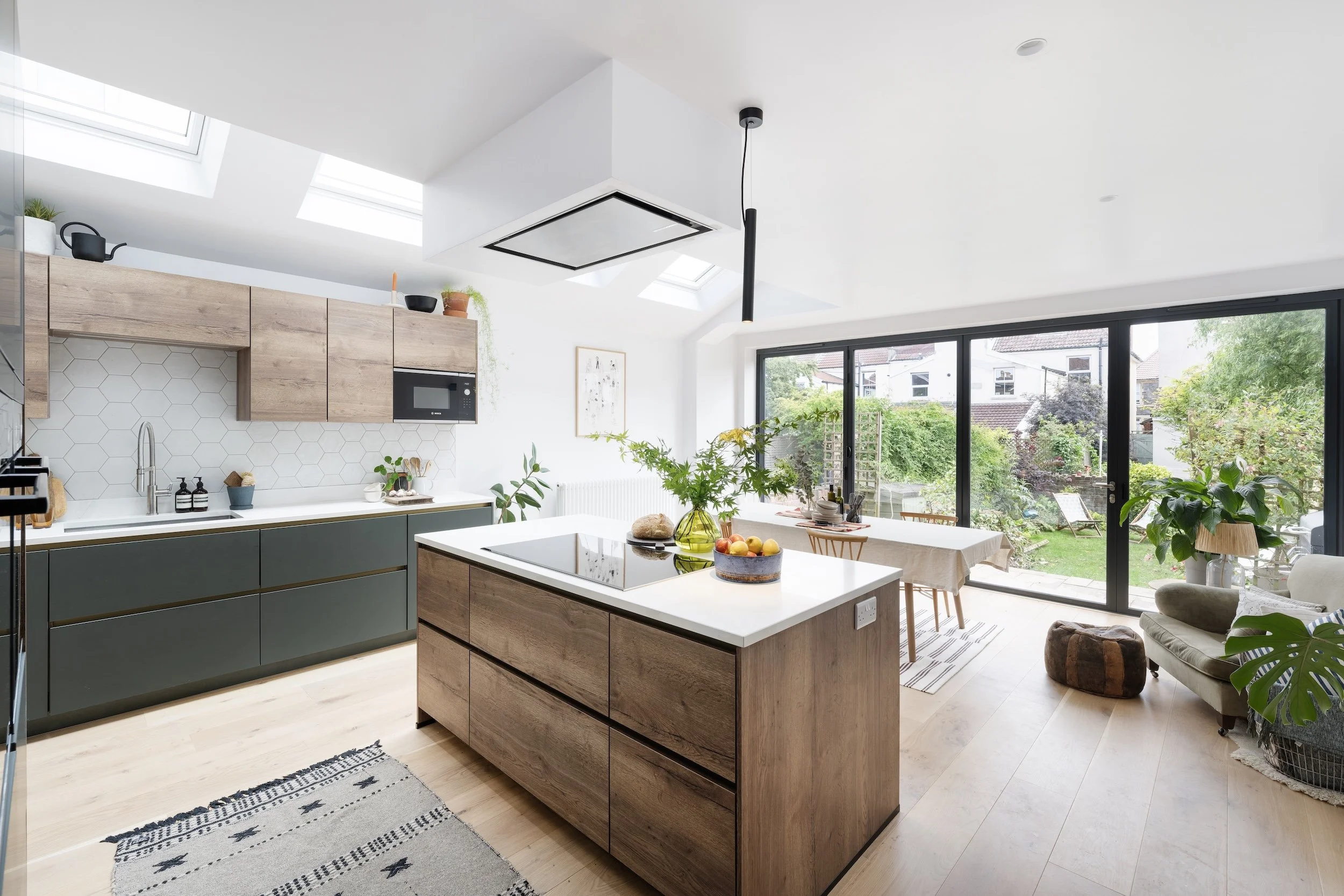 Open-plan kitchen extension with roof lights, an oak-effect island and bi-fold doors onto the garden, in North Bristol by JG Build.