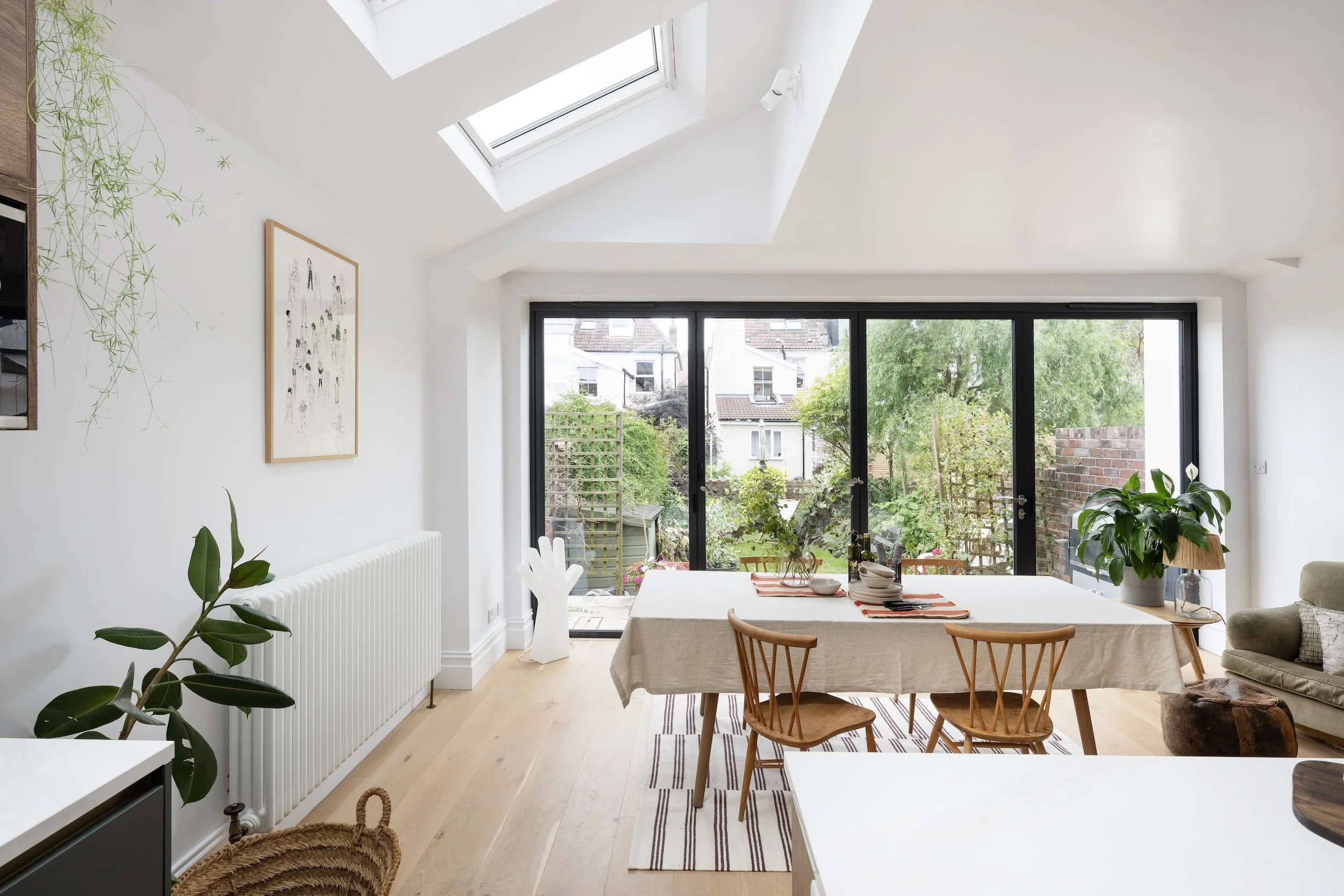 Dining area in a rear extension with a vaulted ceiling, roof lights and bi-fold doors opening onto the garden, in North Bristol by JG Build.