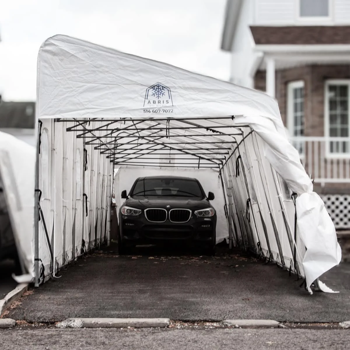 Voiture noire dans un garage mobile avec toiture blanche.
