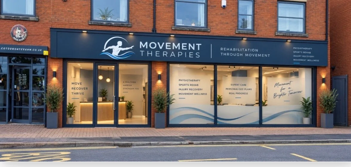 storefront of Movement Therapies with large glass windows and a signboard. The signboard features a logo of a person running and the business name. The windows display text promoting physiotherapy, sports rehab, injury recovery, and wellness services, along with motivational phrases.
