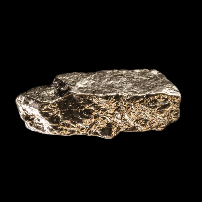 A metallic, irregularly shaped gold nugget against a black background.