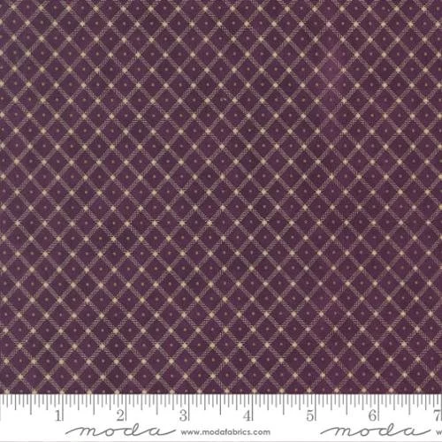 Close-up of purple fabric with a gold diamond pattern and small gold dots at the intersections, with a white ruler at the bottom for scale.