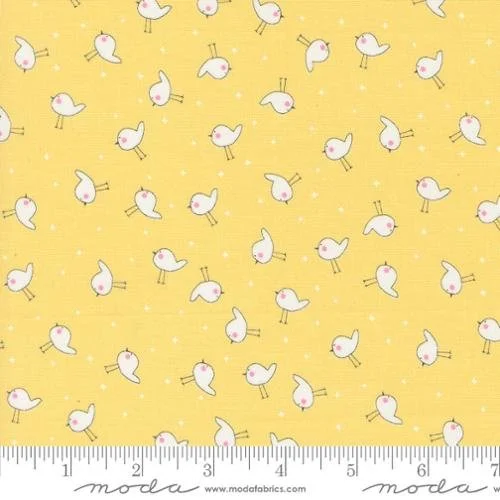 Yellow fabric with small white cartoon ducks and tiny yellow dots, accompanied by a ruler at the bottom for scale.