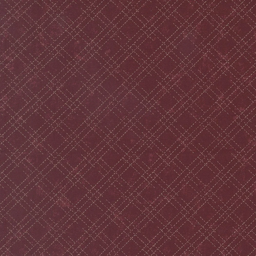 Close-up of a red fabric with a diamond and dashed line pattern.