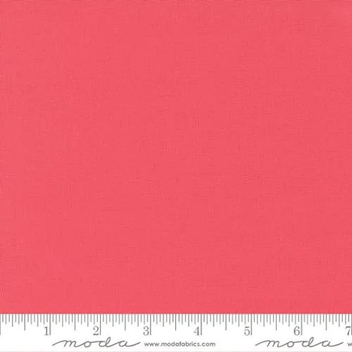 Solid pink fabric with a ruler at the bottom showing measurements in inches