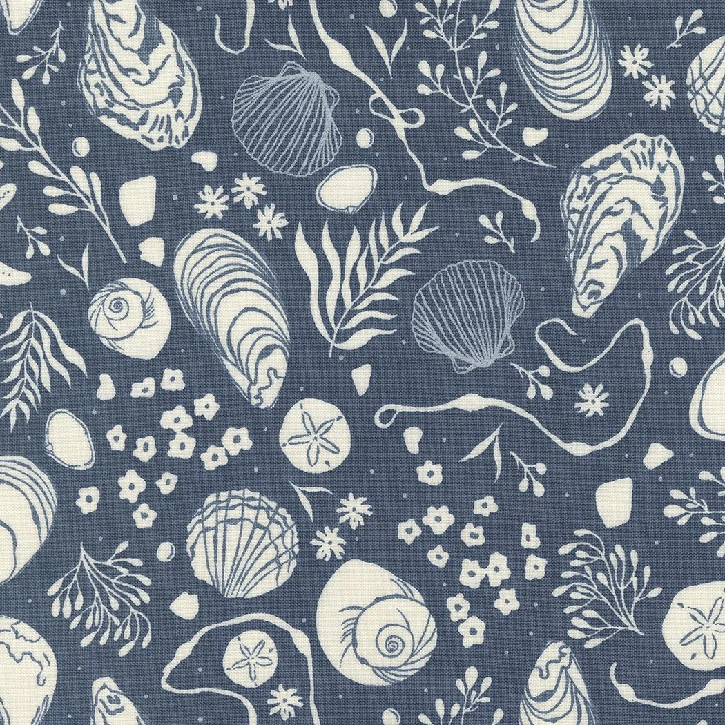 Navy blue fabric with white seashells, starfish, seaweed, and small flowers in a nautical pattern.