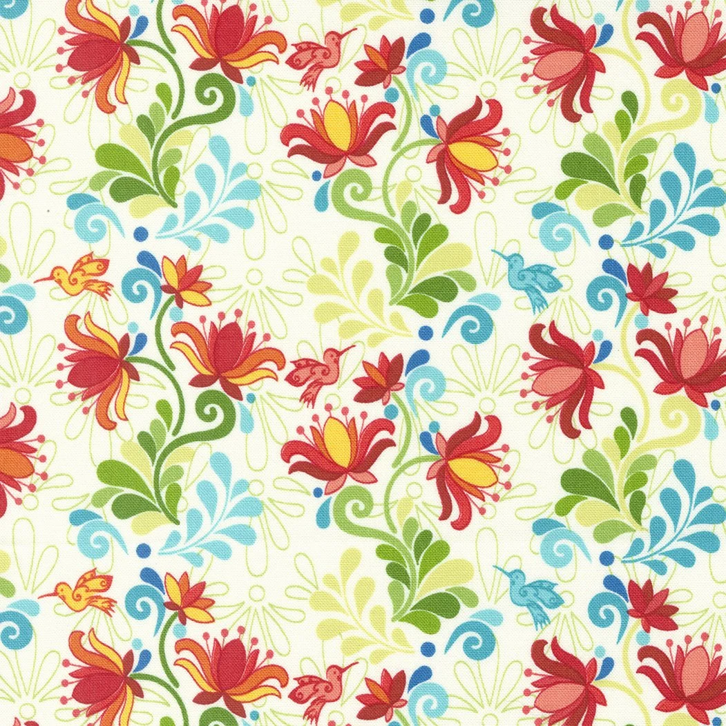 Pattern of red, yellow, and orange lilies with green leaves, blue swirling accents, and small hummingbirds on a cream background.