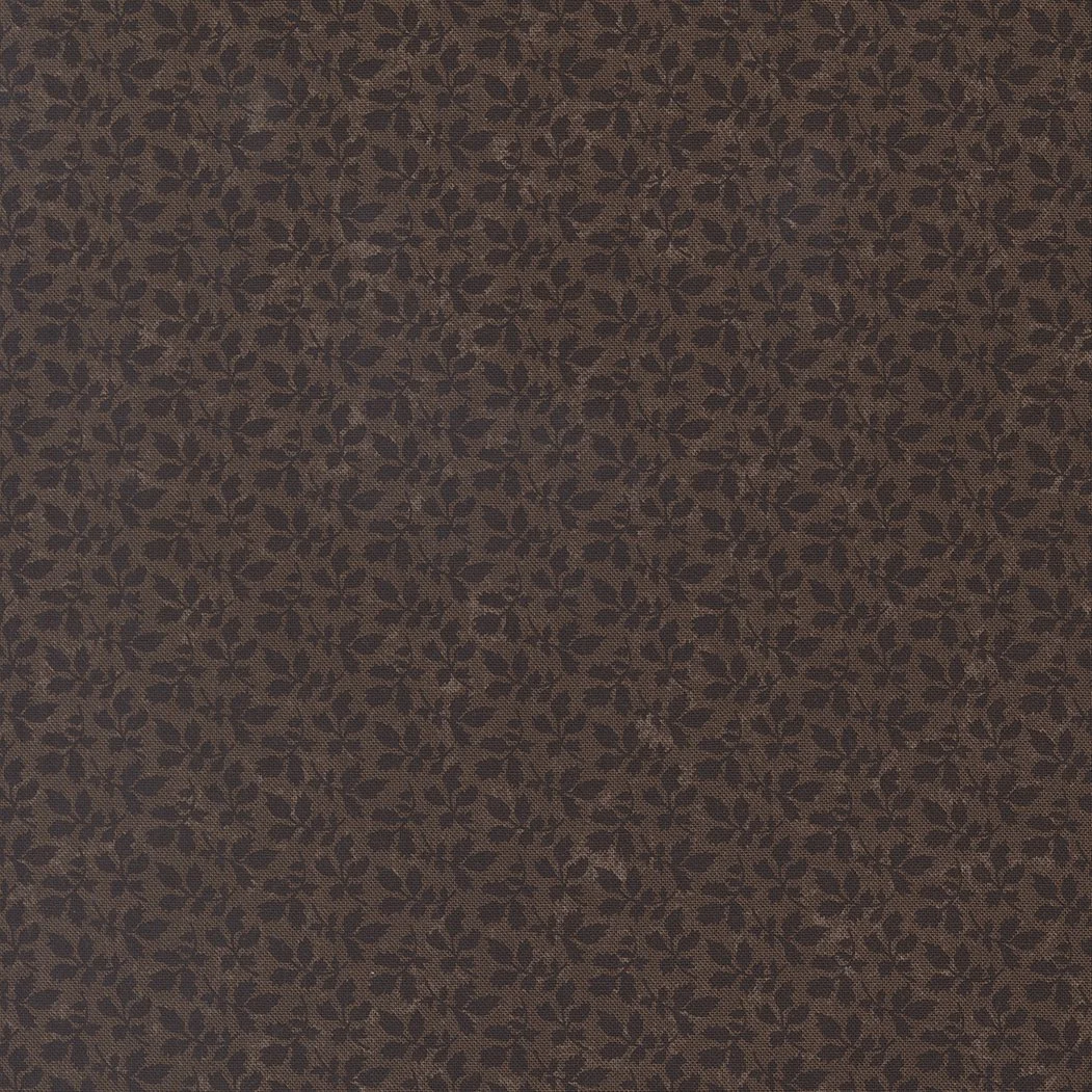 Close-up of a fabric with small, dark, leaf-like patterns on a brown background, creating a dense, repetitive floral design.