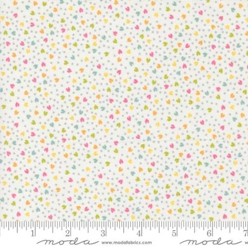 Fabric with small multicolored heart-shaped patterns on a white background, with a ruler at the bottom for scale.