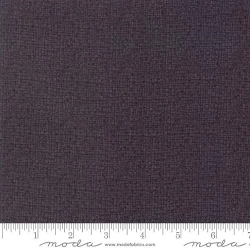 Close-up of dark brown textured fabric with a ruler at the bottom showing measurements.