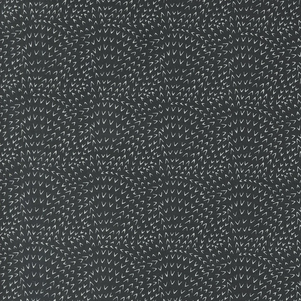 Pattern composed of numerous small, white, V-shaped marks on a black background, creating a swirling, mosaic-like design.
