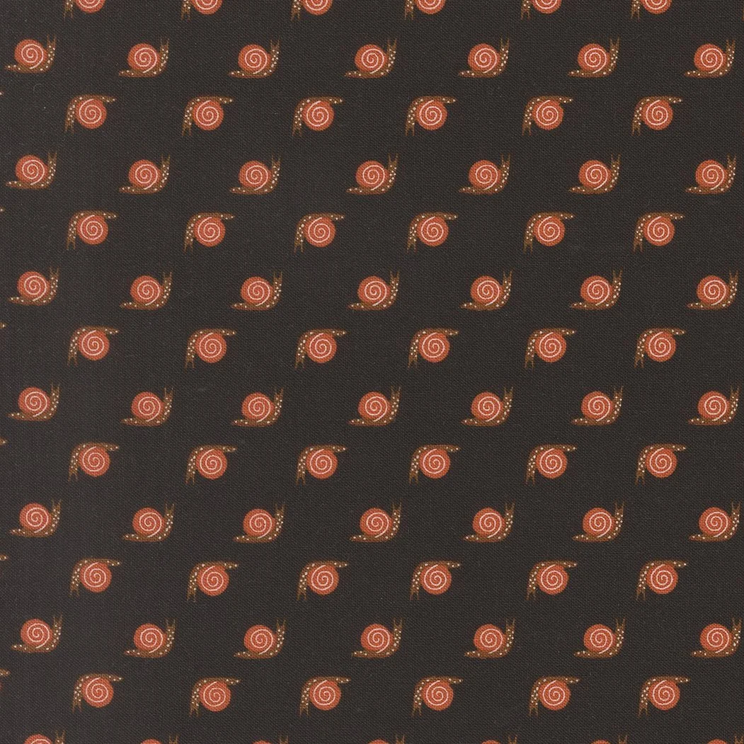 Close-up of a black fabric with a repeating pattern of small red and pink spirals and orange dots.
