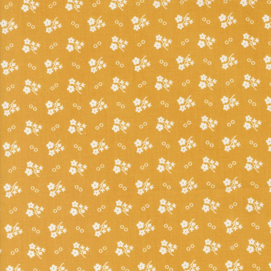 Orange fabric with a white floral pattern consisting of small flowers and concentric circles.
