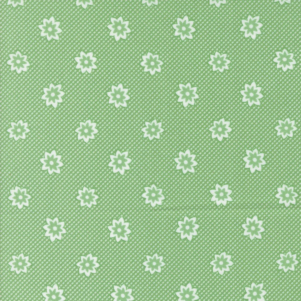 Green fabric with a repeating pattern of white flower shapes and small white dots.