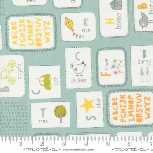 A children's educational fabric print featuring alphabet letters, words, and illustrations of objects such as a kite, house, bunny, bicycle, robot, chicken, flower, tree, and star on a light blue background.