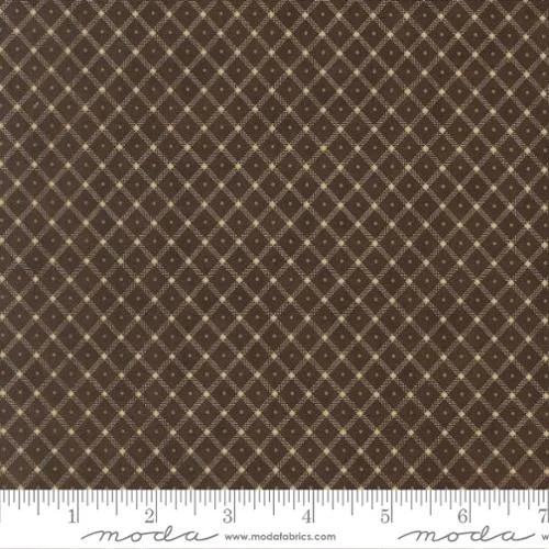 Close-up of brown fabric with a small beige diamond pattern and tiny white dots at the intersections, with a measuring tape at the bottom.