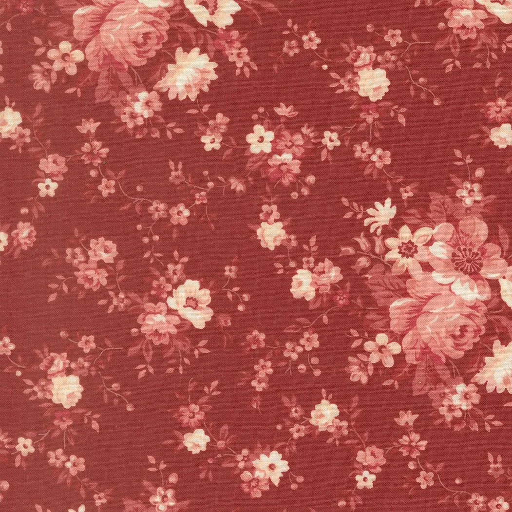 A close-up of red fabric with a floral pattern in pink and cream colors.