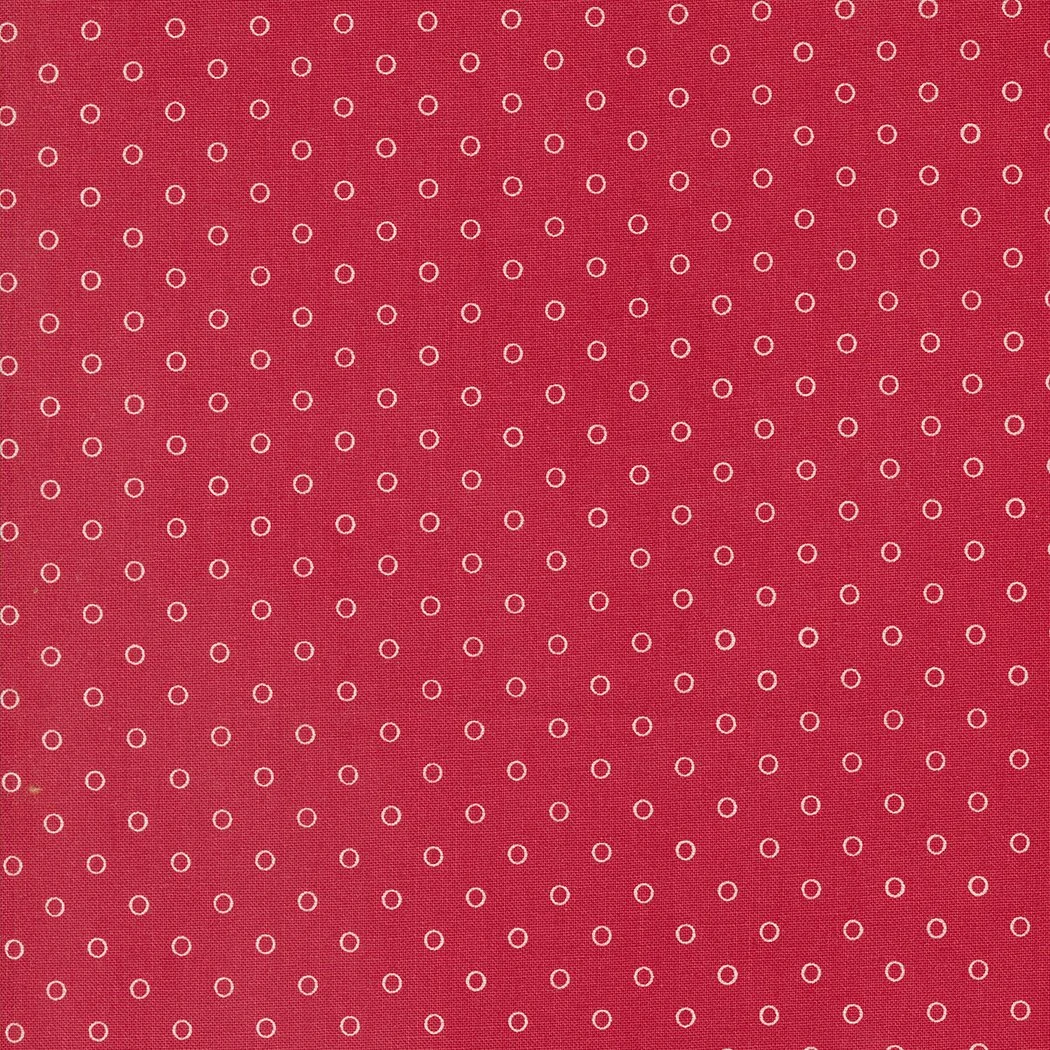 Red fabric with small white rings arranged in a grid pattern.