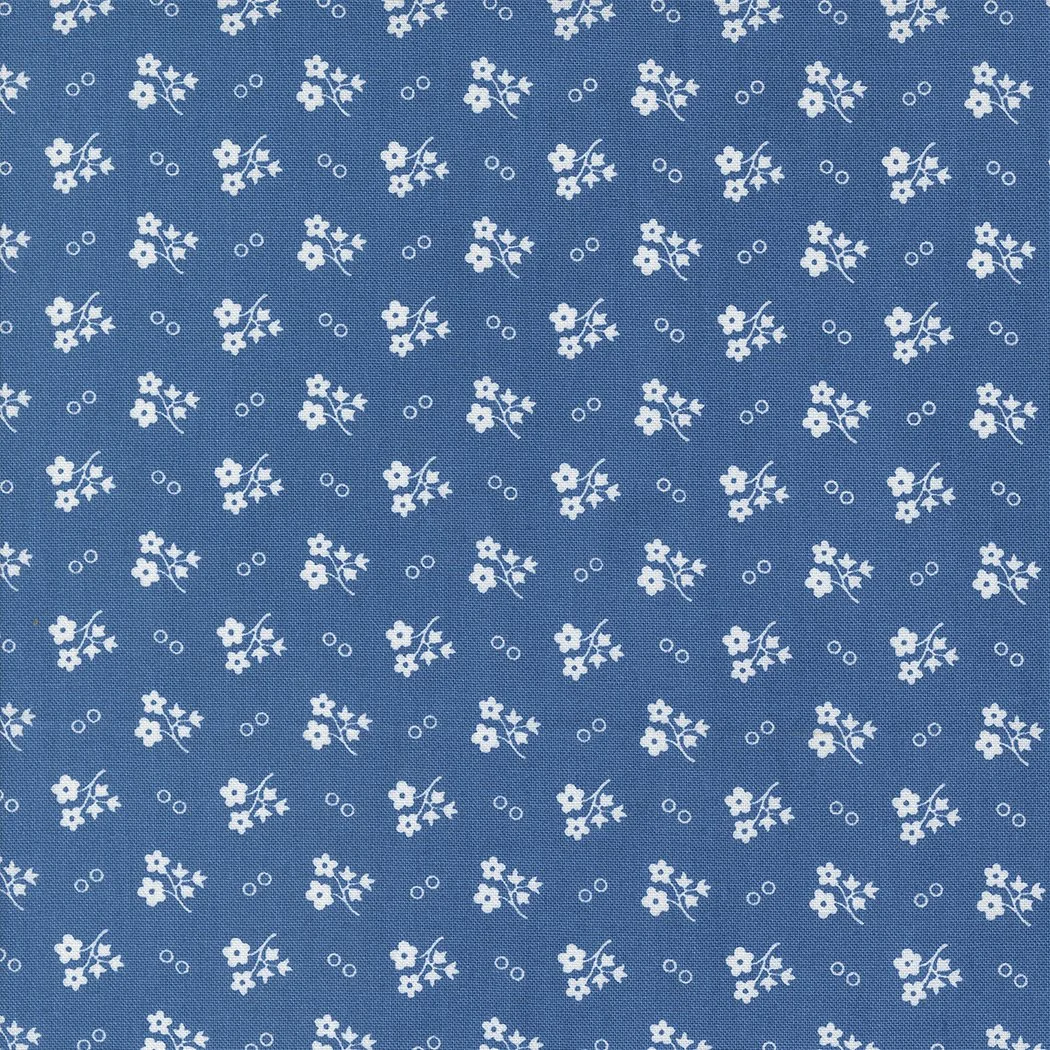 A blue fabric background with a repeating pattern of small white flowers and tiny circles.
