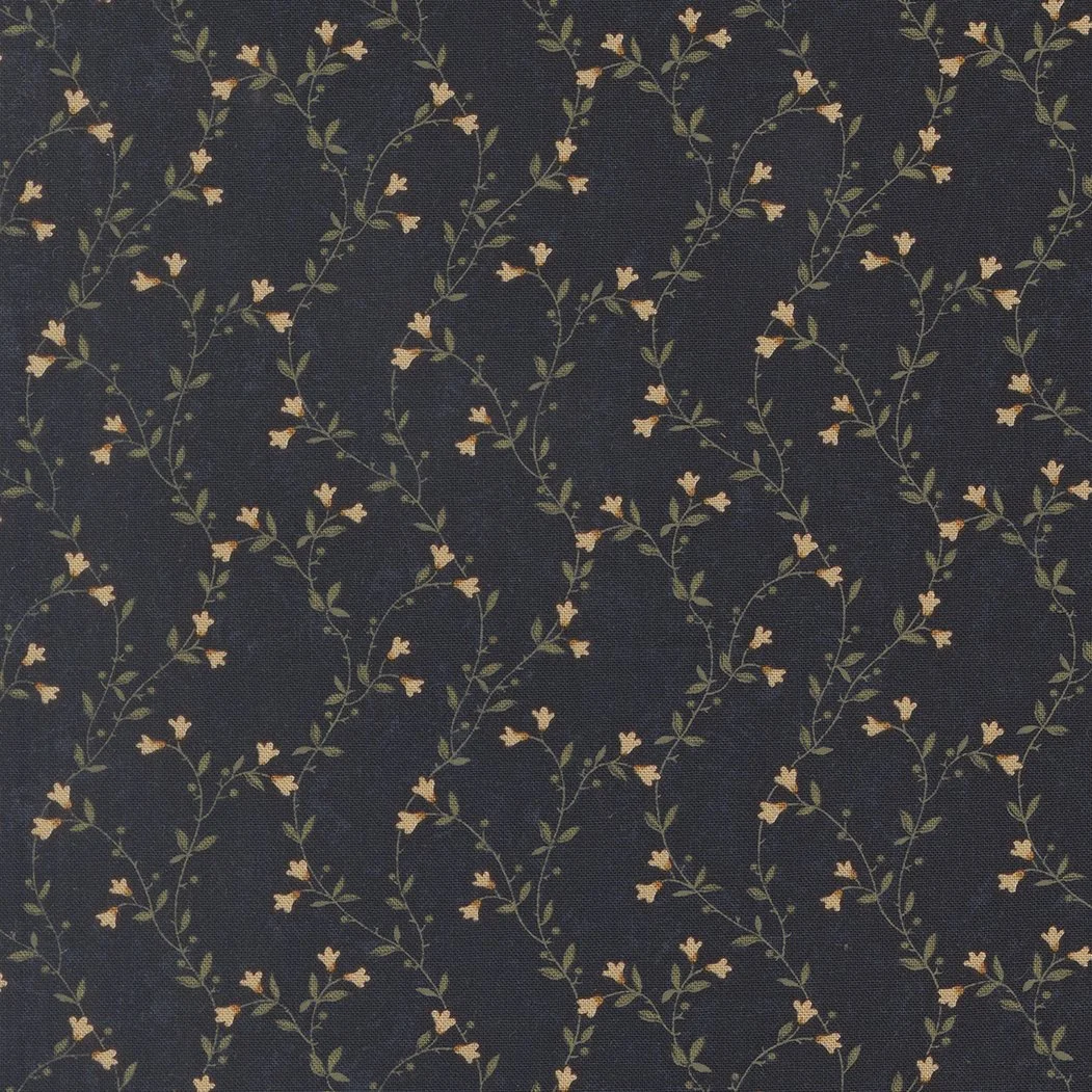 Close-up of fabric with a dark background and a repeating pattern of small, light-colored flowers and green leaves.