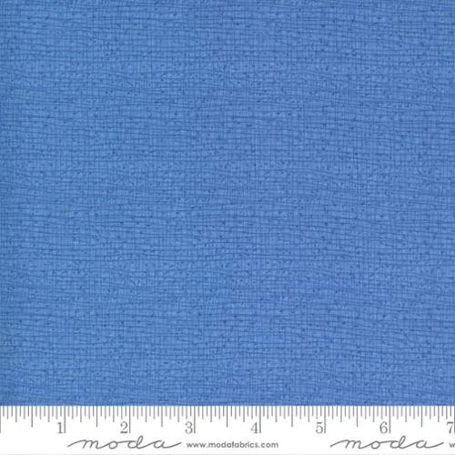 Close-up of blue textured fabric with a ruler at the bottom showing measurements.
