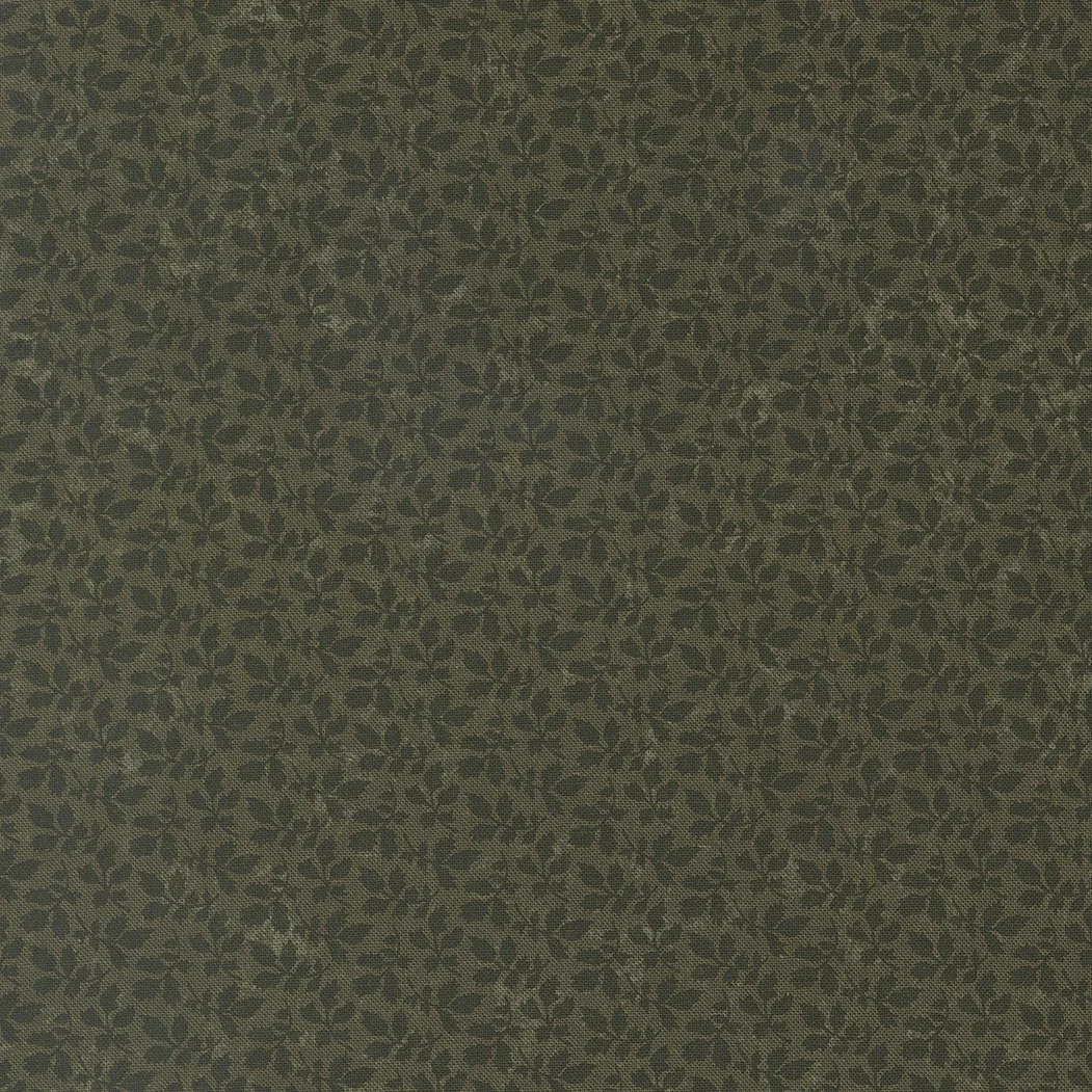 Close-up of fabric with a dark green and olive botanical leaf pattern.