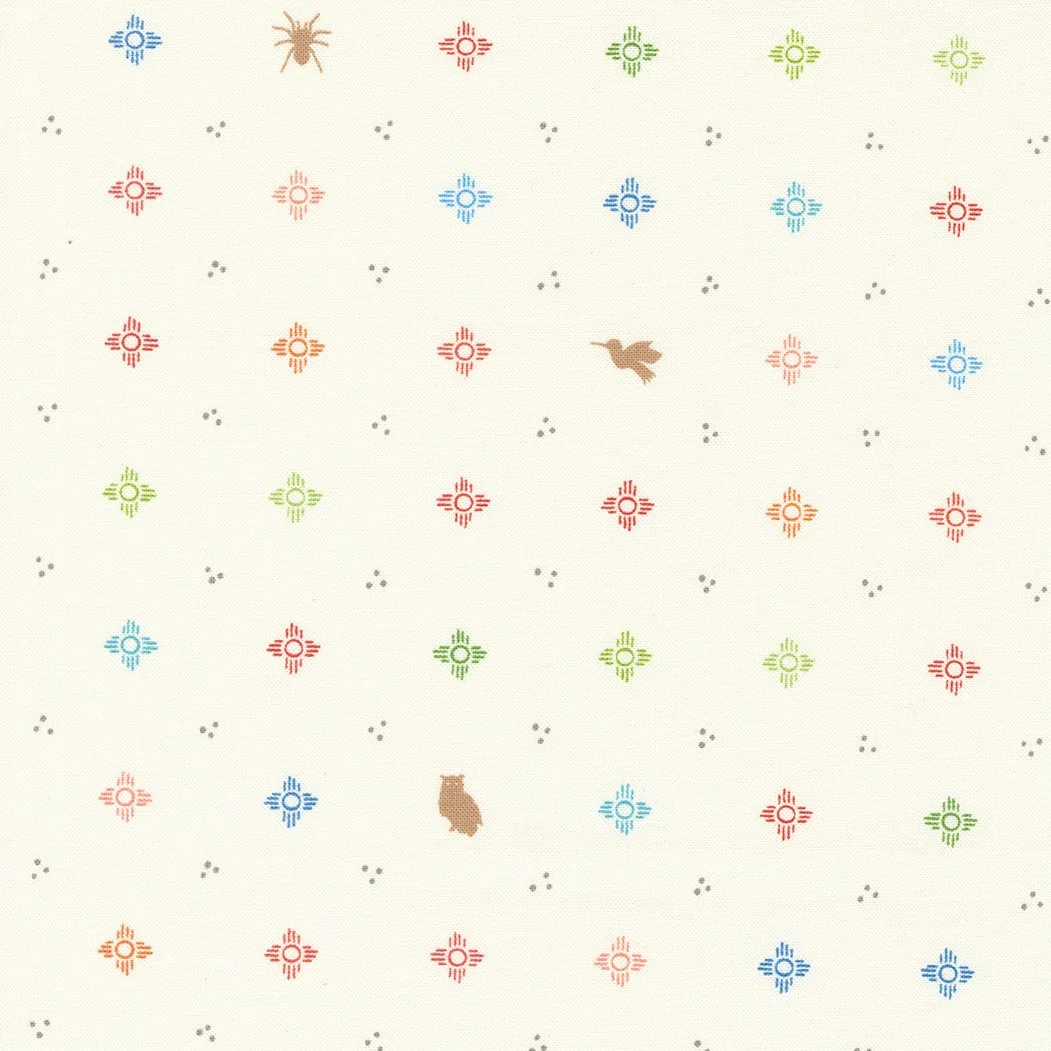 A patterned fabric featuring colorful Navajo symbols in red, green, blue, and orange, along with two brown animals and small gray dots scattered throughout.