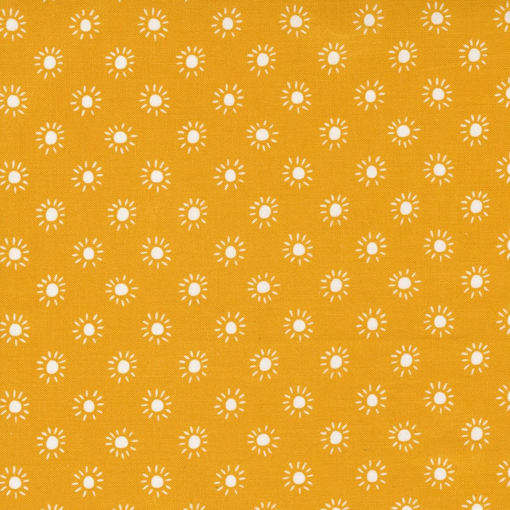 Yellow fabric with a pattern of white sunburst shapes evenly spaced across the fabric.