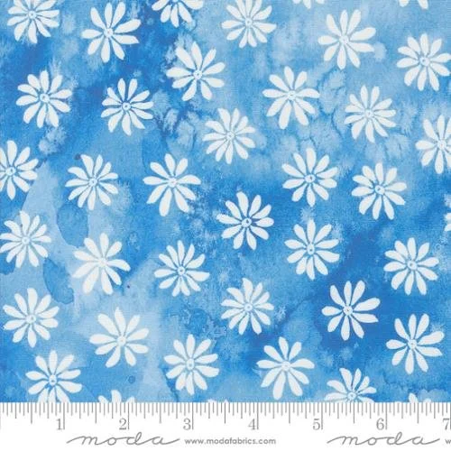 Blue fabric with white daisy patterns and a ruler at the bottom.