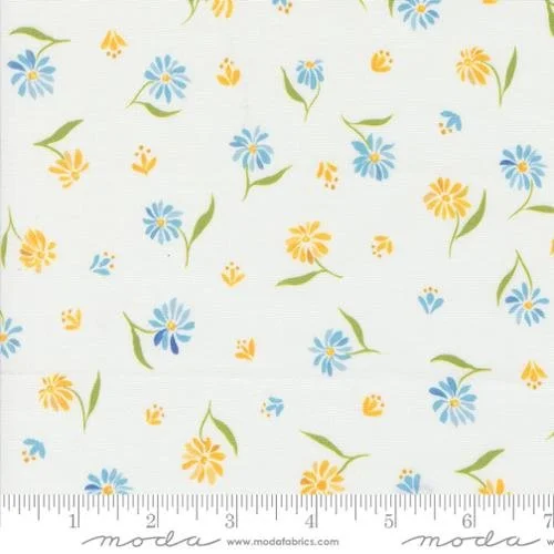 Fabric with a pattern of blue and yellow flowers and green leaves on a white background.