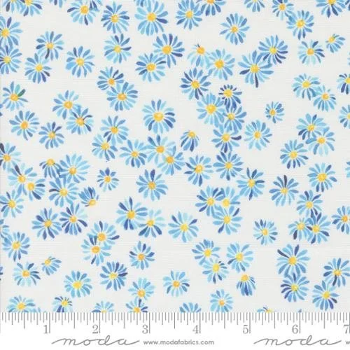 Fabric with a pattern of small blue and white daisies with yellow centers, and a measurement ruler at the bottom.