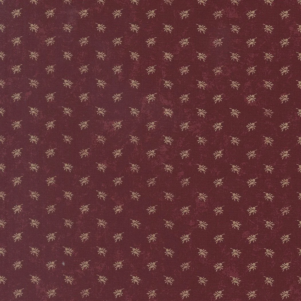 Red fabric with small gold floral pattern evenly spaced.